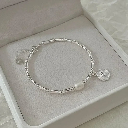 Pulsera de plata con colgante de perla y corazón.